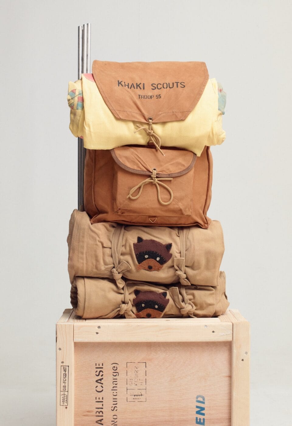 a scout kit including a backpack that reads 'khaki scouts' and a sleeping roll on a crate