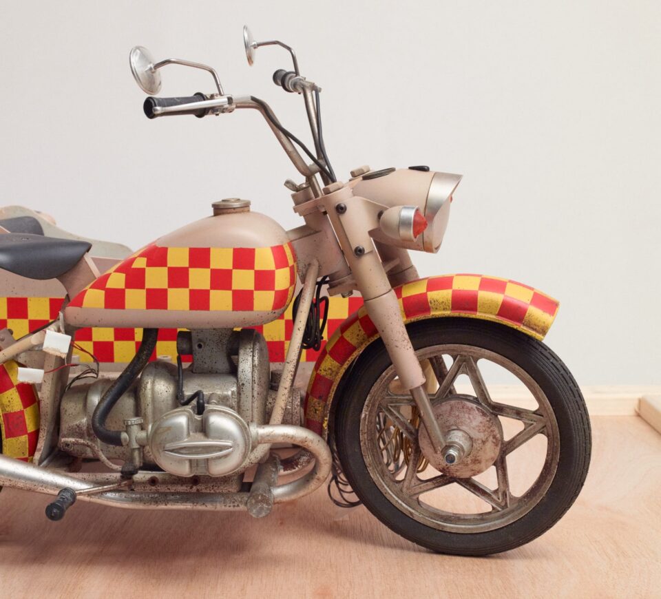 a detail of a miniature motorcycle with red-and-yellow checked design