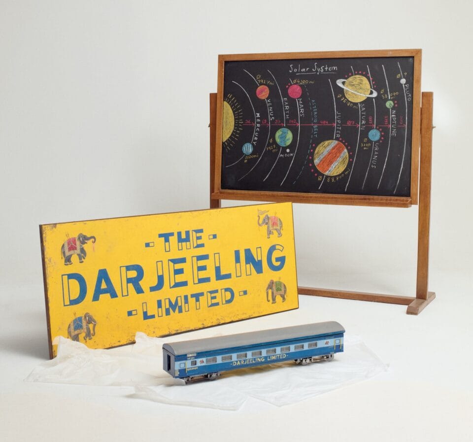 a miniature blackboard with the solar system, a yellow sign reading 'The Darjeeling Limited,' and a miniature train car