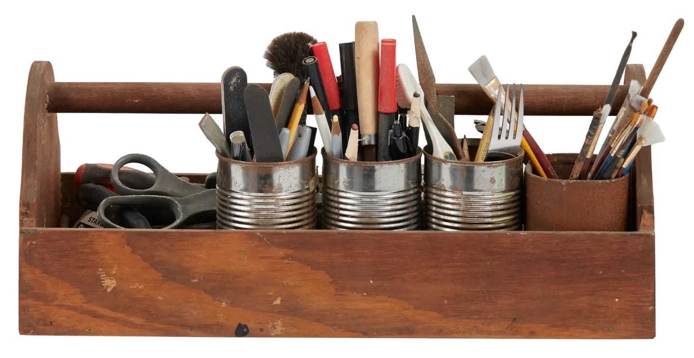 a wooden tool caddy full of tin cans of art supplies