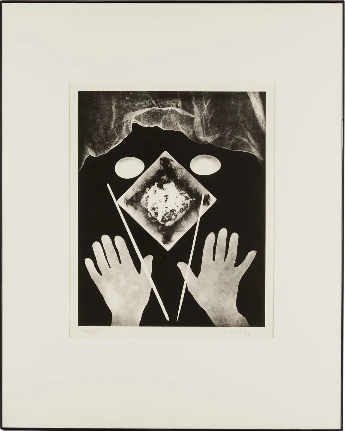 a surrealist black-and-white photo by Man Ray of hands reaching toward chopsticks and a small plate in a composition that resembles a face