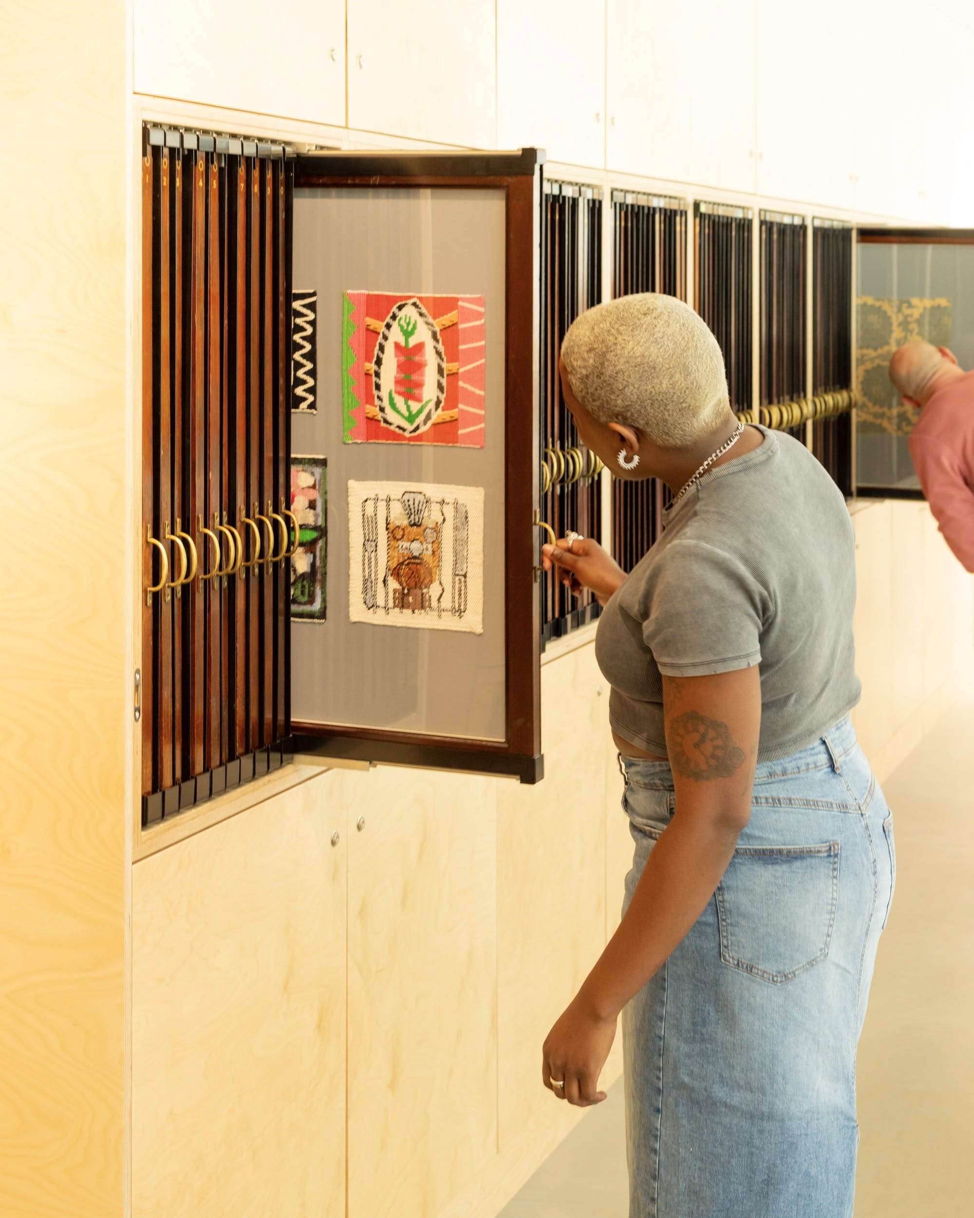 a visitor to a museum storehouse looks at slide-out panels with ephemera